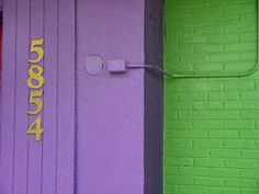 a purple and green building with the number four on it's door is next to a yellow fire hydrant