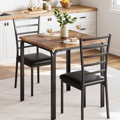 a kitchen table with two chairs and a potted plant on top of it in front of the counter