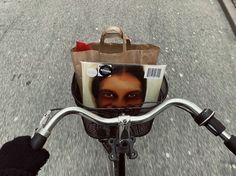 a person riding a bike with a paper bag on the handlebars in front of them