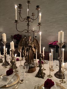 a table topped with lots of candles and angel figurines on top of it