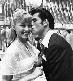 a man kissing a woman on the cheek while standing next to her in front of a crowd