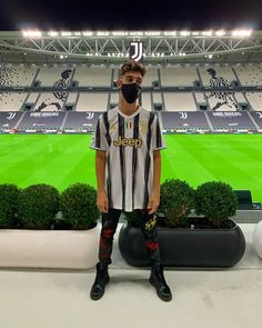 a man standing in front of a soccer field wearing a black and white striped shirt