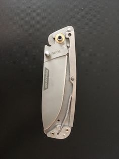 an open folding knife sitting on top of a black surface