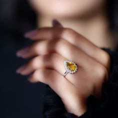 a close up of a person wearing a ring with a yellow stone in the middle