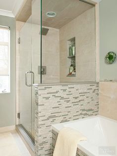 a white bath tub sitting next to a walk - in shower under a bathroom mirror