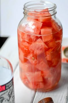 a jar filled with sliced up carrots on top of a wooden table next to a bottle