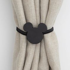 a mickey mouse head is attached to the curtain in front of a white wall and beige fabric