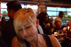 a woman sitting at a table in a restaurant with her eyes closed and hands behind her head