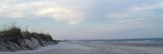 a sandy beach next to the ocean under a cloudy sky