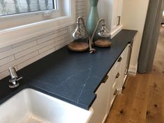 a kitchen counter with two vases on it and a sink in front of the window