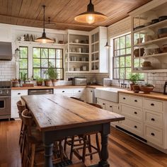 a large kitchen with wooden floors and white cupboards, an island in the middle