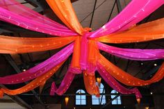 the ceiling is decorated with orange, pink and purple ribbon draped over it's head