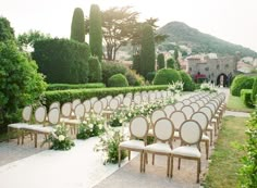 rows of chairs with white flowers and greenery in front of an outdoor ceremony venue