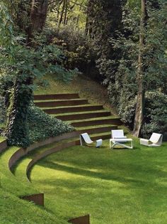 some white chairs sitting in the middle of a grass field with stairs leading up to it