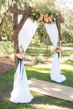 an outdoor wedding ceremony setup with white drapes and flowers on the arch, along with blue ribbon