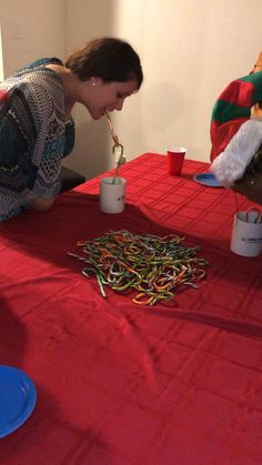 a woman bending over to pick up some colorful streamers from a table with cups on it