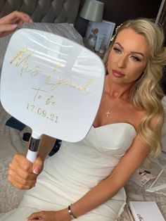 a woman in white dress holding up a fan with writing on it