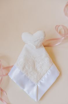 a white wedding dress and pink ribbon on a table