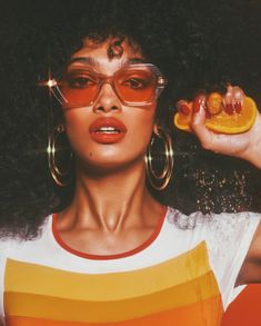 a woman with large hoop earrings holding an orange slice in front of her face and the words hot stuff on it