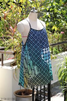 a dress on a mannequin next to potted plants in a fenced area