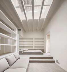 a living room filled with white furniture next to a wall covered in bookshelves