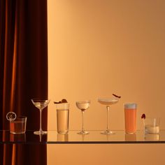 there are many glasses on the table with different drinks in them and one is empty