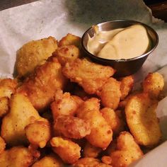 some fried food is sitting in a basket with a dipping sauce on the side and it's ready to be eaten