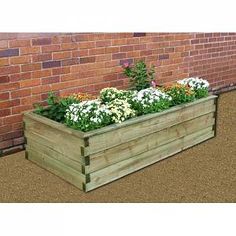 a wooden planter filled with flowers next to a brick wall