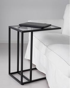 a black metal and glass side table on a white couch