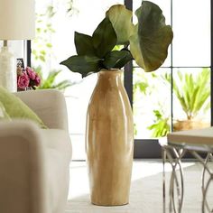 a vase with some flowers in it sitting on the floor next to a couch and table