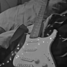 an electric guitar sitting on top of a bed next to a black and white photo