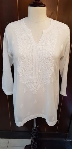 blouse in white with neck lace trim and full sleeves . hand embroidered by skilled artisans. fabric is cotton 2x2 weave. sizes available are S - BUST 36 INCHES M - BUST 38 INCHES L - BUST 40 INCHES XL - BUST 42 INCHES 0XL - BUST 44 INCHES LENGHT OF THE STYLE VARIES FROM 28 INCHES FOR THE SMALL SIZE UPTO 31 INCHES FOR THE OXL SIZE Long Sleeve Cotton Blouse With Resham Embroidery, Festive Long Sleeve White Blouse, Traditional Long Sleeve Cotton Blouse Piece, Traditional Long Sleeve Cotton Blouse, Cotton Chikankari Embroidery Long Sleeve Blouse, White Long Sleeve Blouse For Festive Occasions, Traditional White Festive Top, Traditional White Embroidered Festive Top, Traditional Long Sleeve Blouse With Chikankari Embroidery