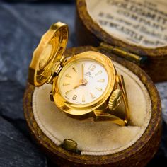 This vintage Bucherer fold top watch ring dates from around the 1920's. The ring is crafted in naturally patinated 18k yellow gold. The watch currently keeps at least 2 hours of time, however, the ring is more meant for fashion as opposed to time-keeping. We are not able to offer a warranty on the movement.  The hallmarks from Switzerland that indicate it was made between 1917 and 1934. Vintage Formal Watches With Rotating Bezel, Vintage Jewelry With Rotating Bezel For Formal Occasions, Victorian Yellow Gold Watches For Anniversary, Classic Formal Ring With Rotating Bezel, Victorian Yellow Gold Anniversary Watch, Vintage Yellow Gold Hallmarked Watch, Antique Yellow Gold Self-winding Watch, Victorian Yellow Gold Self-winding Watch, Antique Self-winding Yellow Gold Watch