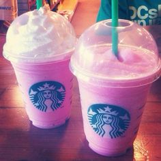 two pink starbucks drinks with whipped cream on top and green straws in each cup