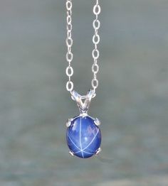 "A stunning new necklace made using a star sapphire gemstone. The sapphire is oval shaped and cabochon cut. It is excellent quality and set into a sterling silver prong setting. Lab grown Sapphire measures 10mm tall (just under 1/2\") while entire pendant is roughly 1/2\" tall. It hangs from sterling silver chain. Please choose desired chain length at checkout. Please see matching ring and earrings here: https://www.etsy.com/shop/hangingbyathread1?ref=search_shop_redirect&search_query=star+s Star Sapphire Gemstone, Sapphire Pendant Necklace, Oval Pendant Necklace, Sapphire Birthstone, Sapphire Necklace Pendants, Jewelry Dainty, Matching Ring, Star Sapphire, Sapphire Pendant