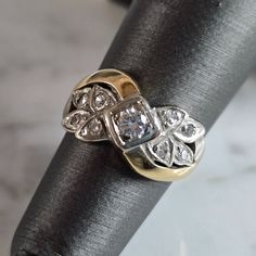 a gold and silver ring with diamonds on it's side sitting on a black cloth