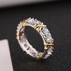 a gold and white diamond ring on a black surface