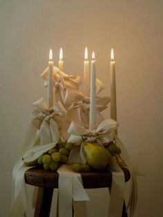 a table topped with candles and fruit on top of a wooden table covered in ribbons