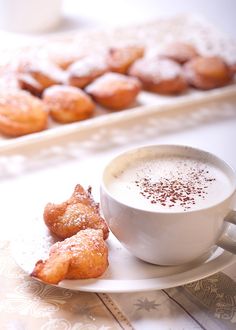 a cup of cappuccino and some pastries on a white saucer