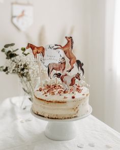 a cake with horses on it sitting on a table next to a vase filled with flowers