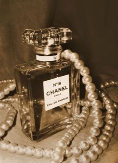 a bottle of chanel perfume sitting on top of a table next to some pearls