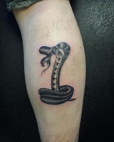 a tattoo on the leg of a man with a snake in it's mouth