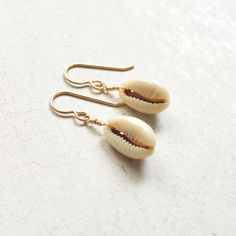 Simple & cute describe these whole cowrie shell earrings! They're the perfect accessory to wear with your favorite casual outfit when you're out & about. Please allow for variations in size and shape of shells as each is unique. Casual Shell Jewelry Gift, Casual Cowrie Shell-shaped Jewelry, Cowrie Shell Dangle Earrings As Gift, Gold Cowrie Shell Earrings For Gift, Gold Cowrie Shell Earrings As Gift, Dangle Cowrie Shell Earrings For Beach, Cowrie Shell Earrings For Gifts, Cowrie Shell Dangle Jewelry For Gifts, Cowrie Shell Dangle Jewelry Gift