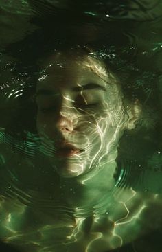 a woman floating in the water with her eyes closed and head above the water's surface