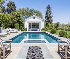 an outdoor pool surrounded by lawn furniture and trees