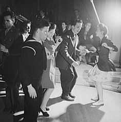 some people are dancing on the dance floor in a black and white photo while others watch