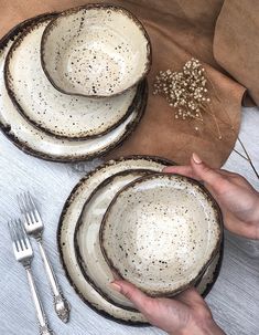 a person is holding three plates with silverware next to each other on a table