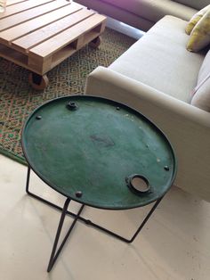 a green tray sitting on top of a metal stand in front of a white couch