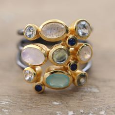 Featuring a dazzling combination of oval and round rainbow moonstone, iolite, blue topaz, onyx and labradorite gemstones set in 18k gold-plated bezels, this cocktail ring is a true masterpiece from the artisans of India. Each gemstone is selected with precision to create a symphony of colors and sizes, perfect for the fashion-forward woman. But the beauty of this breathtaking ring by Neetu Barathi doesn't stop there: the band is made of three oxidized sterling silver strands adding an edgy twist Fusion Style Oval Moonstone Ring, Classic Multi-stone Oval Cabochon Rings, Celestial Multi-stone Moonstone Ring, Celestial Multi-stone Oval Moonstone Ring, Celestial Multi-stone Moonstone Oval Ring, Modern Multi-stone Sterling Silver Gemstones, Bohemian Multicolor Multi-stone Rings, Bohemian Oval Multi-stone Gemstones, Oval Multi-stone Blue Topaz Gemstones