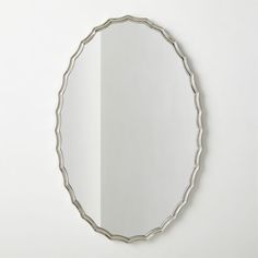 a round mirror hanging on the wall next to a white wall with a reflection in it